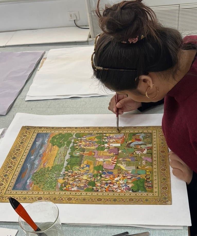 Smriti Rajput inpainting a Mughal miniature painting under a fine brush